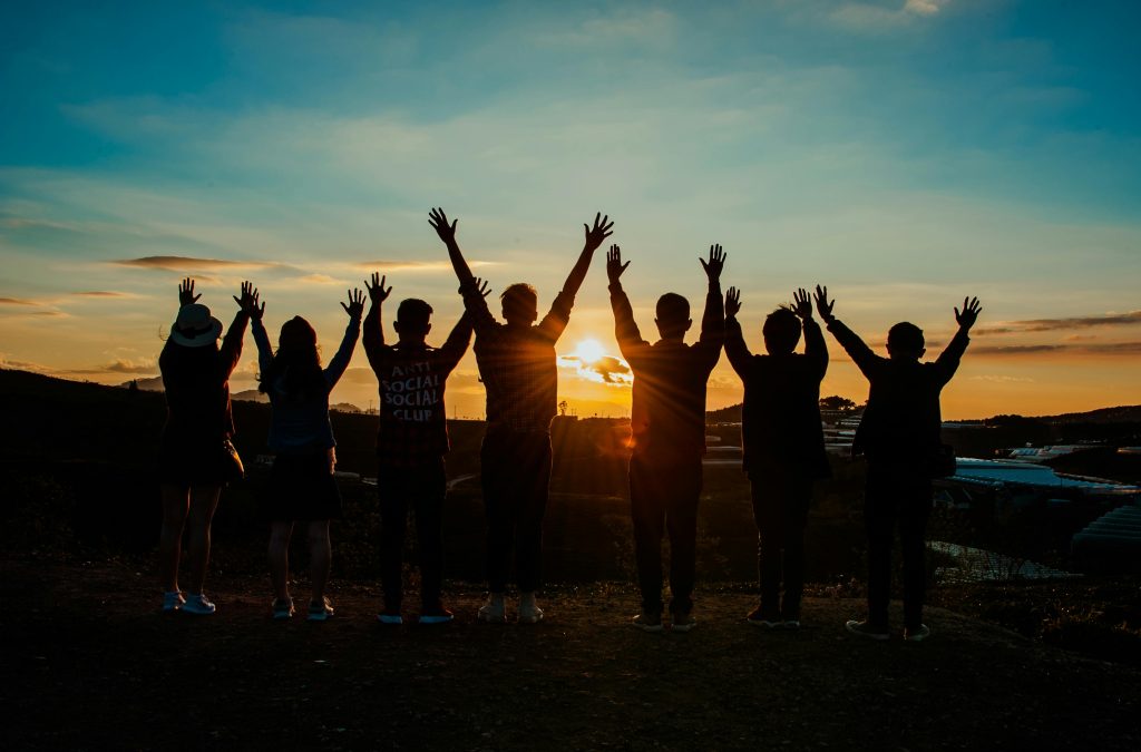 pexels-photo-853168-853168 A diverse group of friends raises their arms in celebration against a vibrant sunset backdrop.